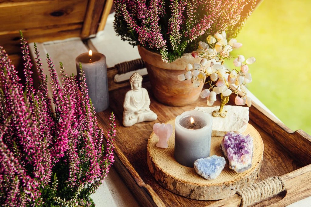 A tray of crystal clusters, candles, statue and a pot of flowering plants