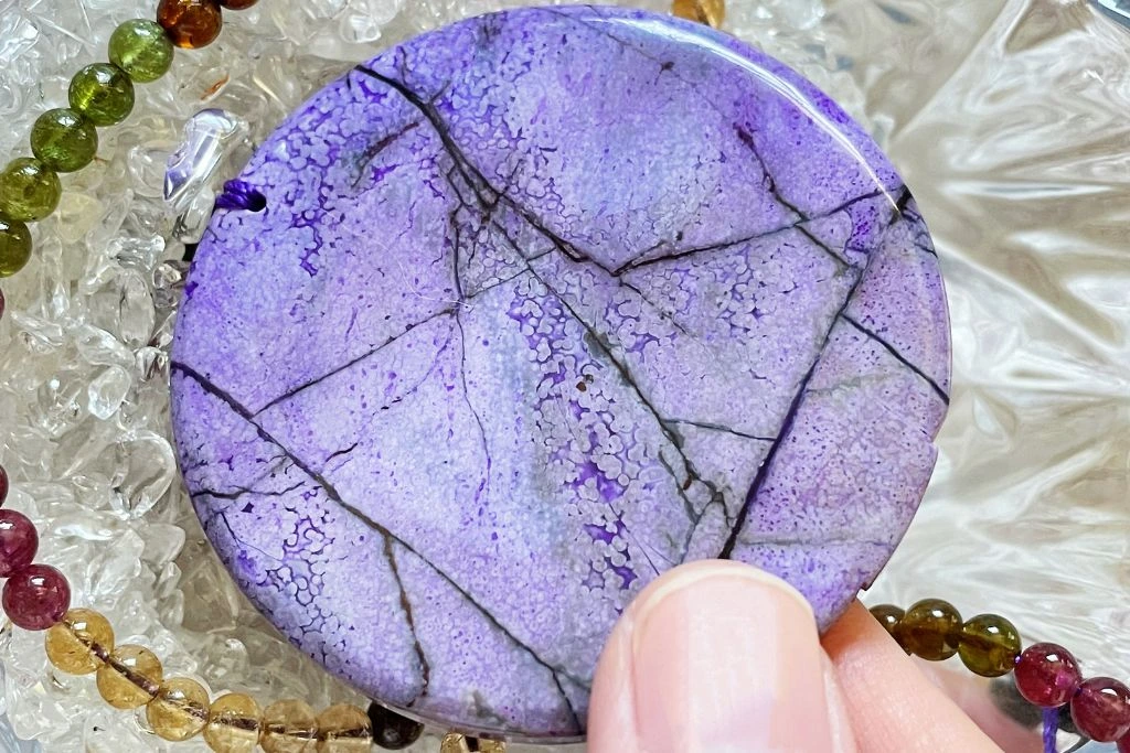 A person holding a sugilite necklace