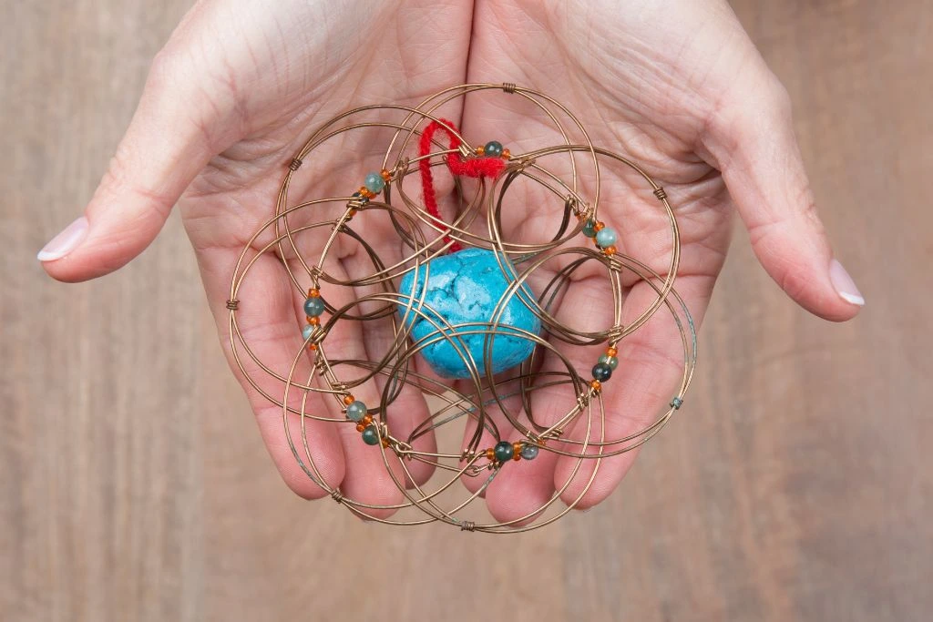 A person holding a Turquoise crystal with metal mandala