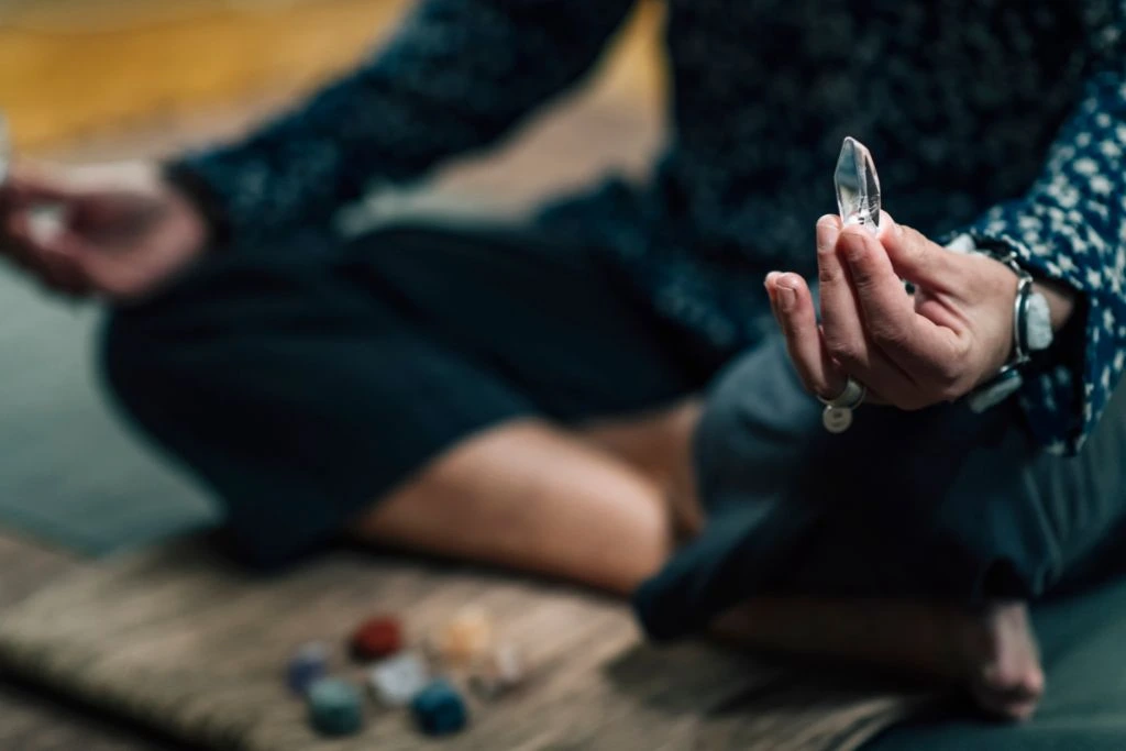 A person holding a crystal wand while sitting 