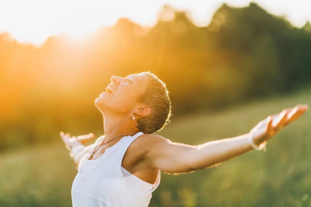 Woman with wide arms open basking on the sunlight