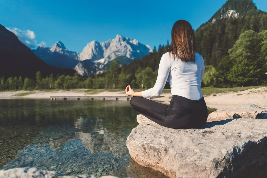 calm woman meditating by the river