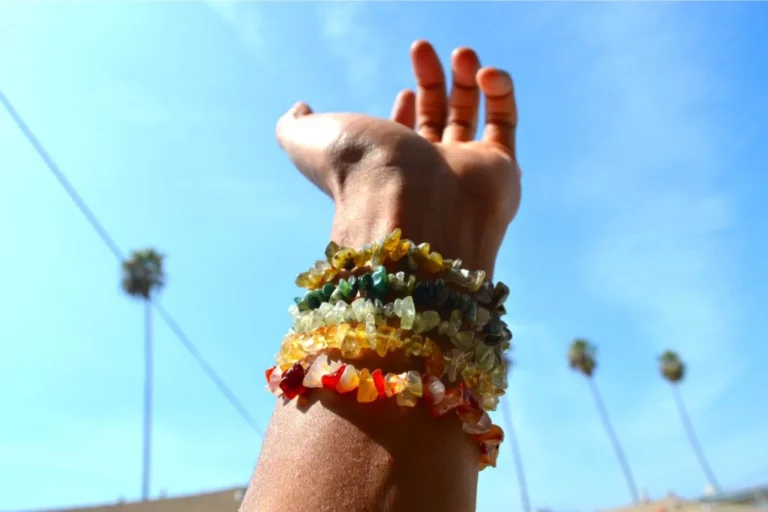female left hand wearing chakra bracelets