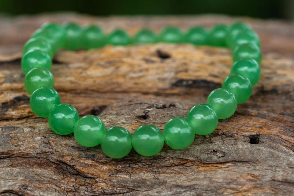 green aventurine bracelet for heat chakra power situated on wood platform