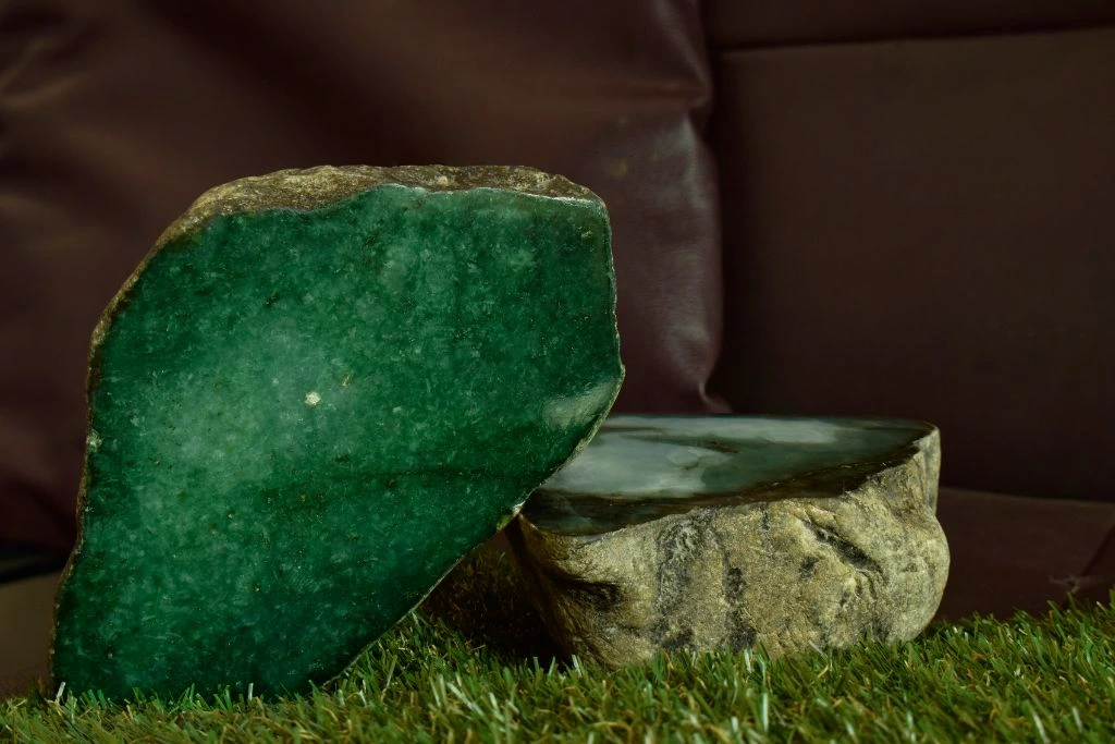green jade crystals on top of a green grass with a leather couch background