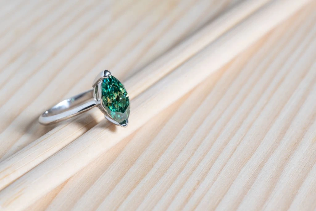 marquise-cut-emerald-ring-situated-on-wood-table