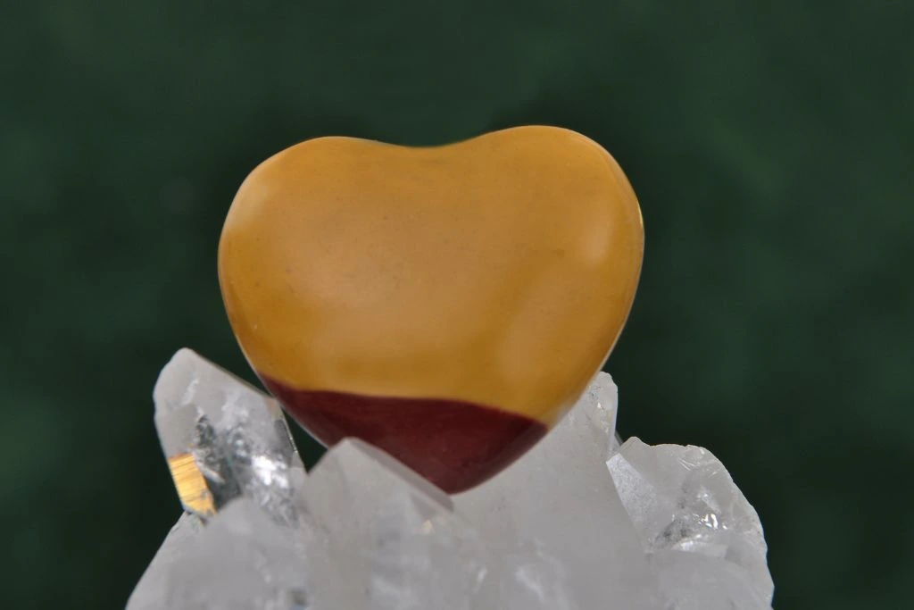 A polished heart shape mookite on top of a rock crystal