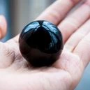 a hand holding an obsidian ball
