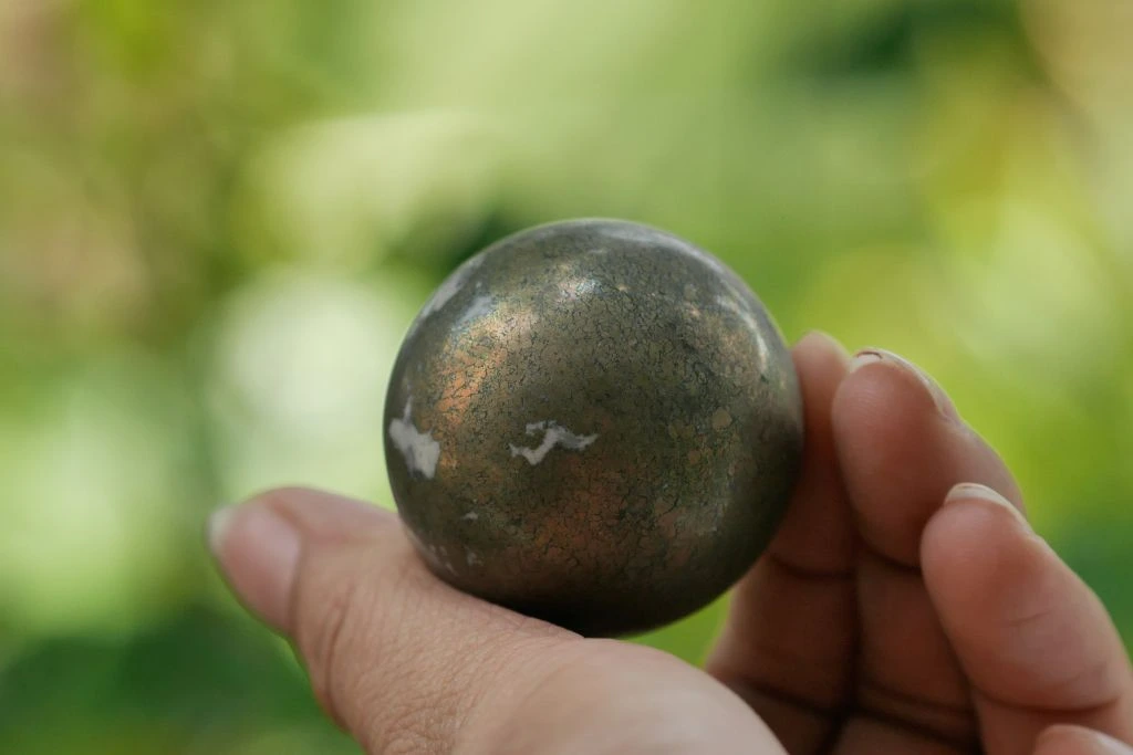 A person holding a pyrite crystal ball