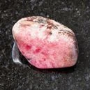 A rhodonite crystal on a black granite