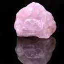 rose quartz on a black background with reflection below