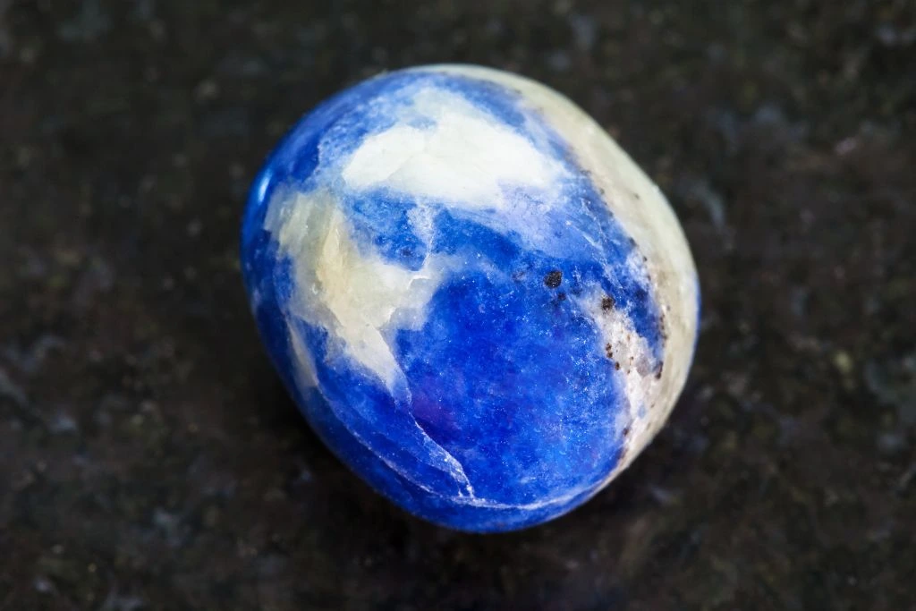 a polished sodalite crystal on a black granite