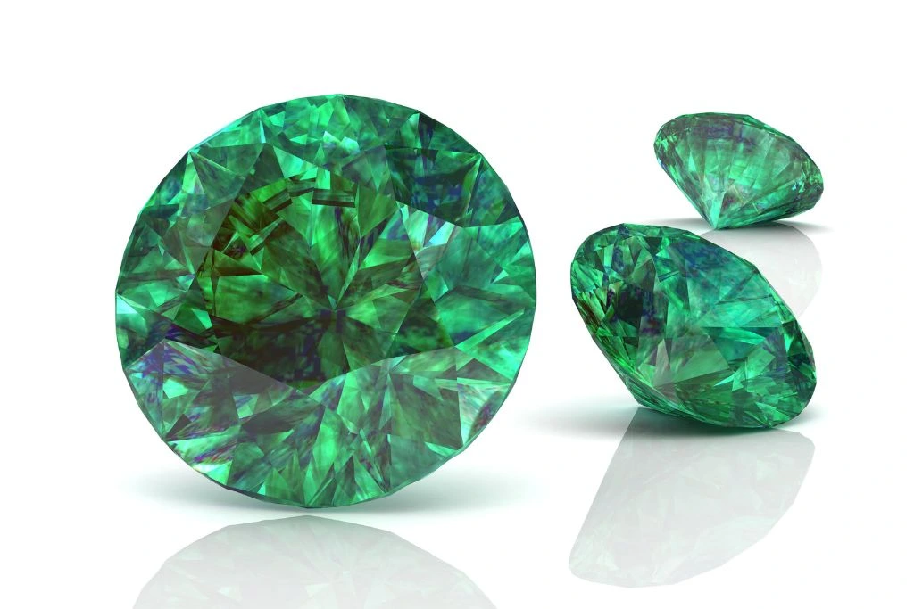 three emerald gemstones on white background