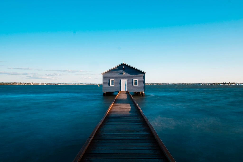 A blue house on the middle of a body of water