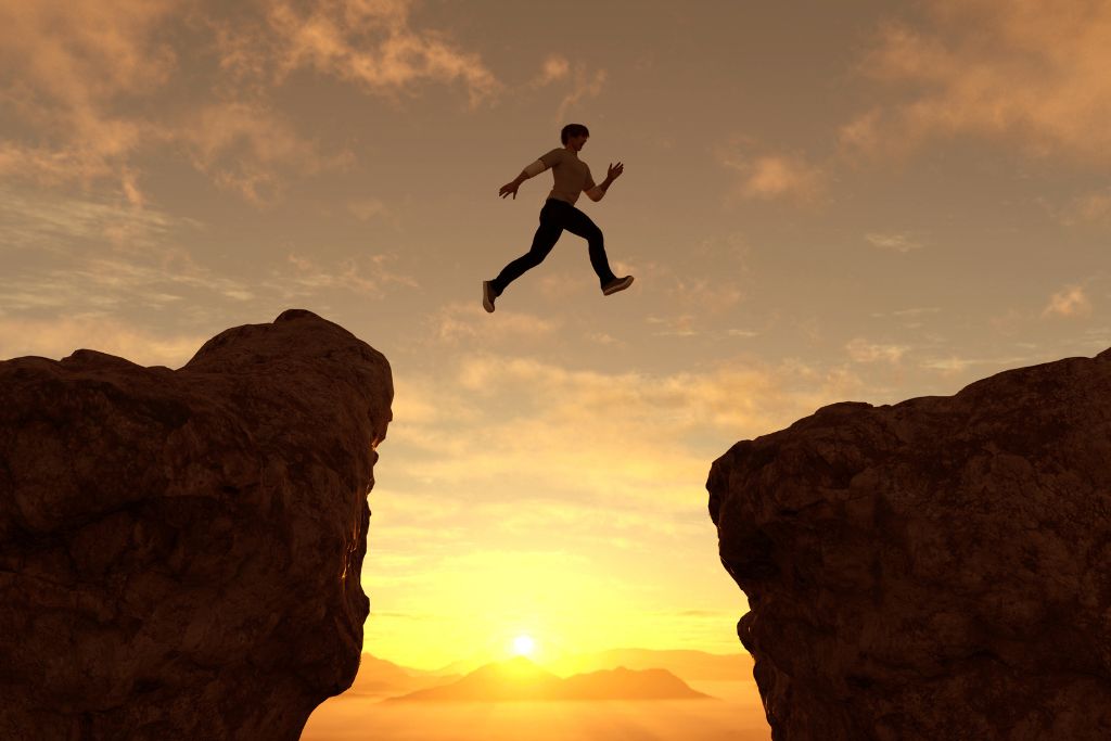 A man jumping from one cliff to another