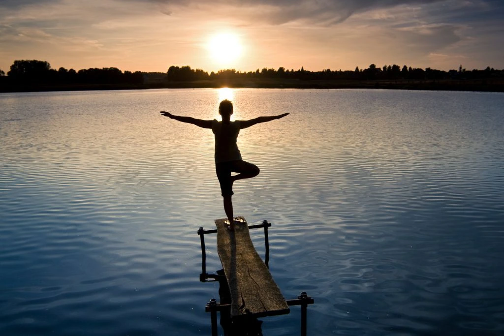 A person balancing with one foot on a wooden plank.