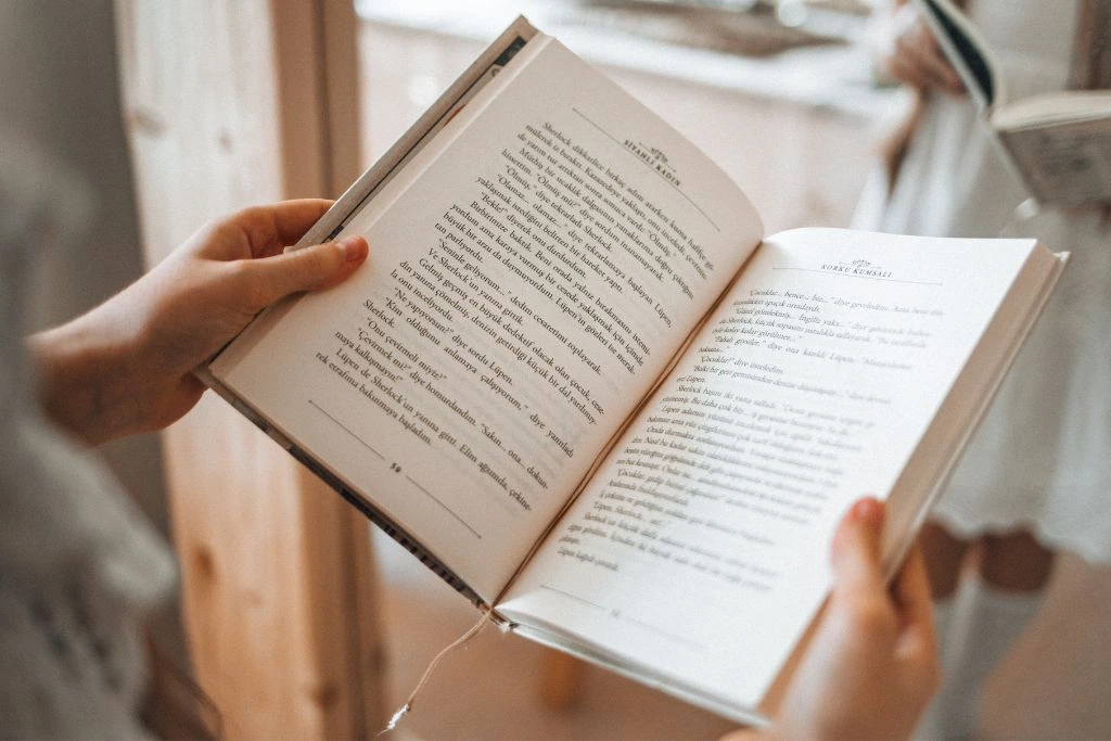 A woman reading a book in front of a mirror