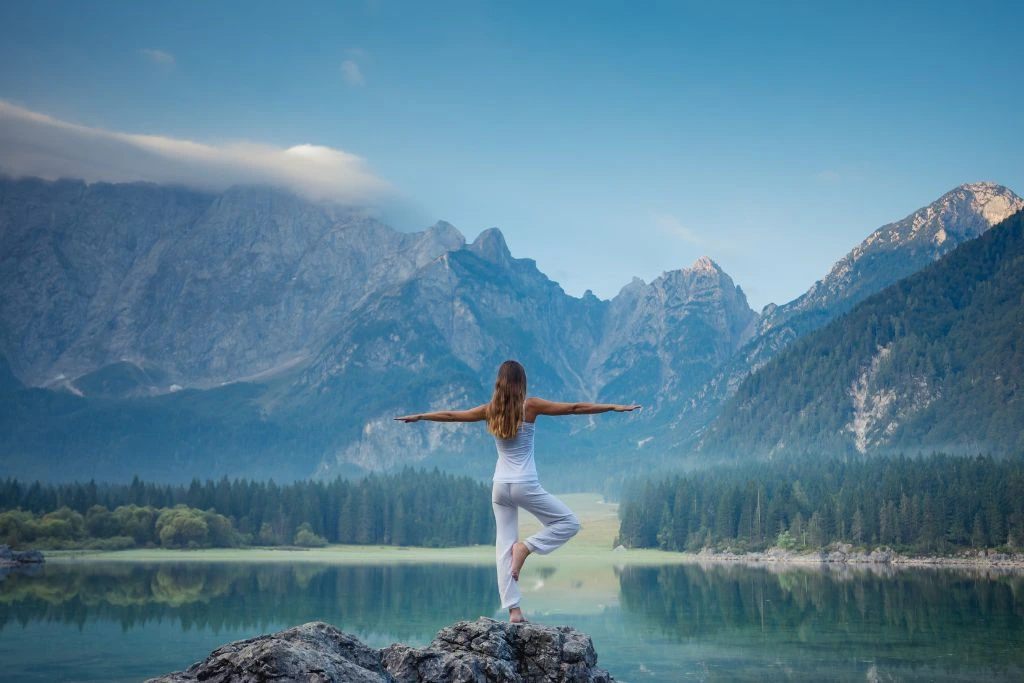 A woman is balancing herself with one foot on top of the cliff