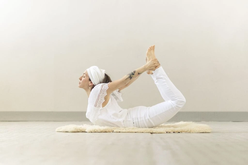a woman doing a bow pose yoga position on a rug