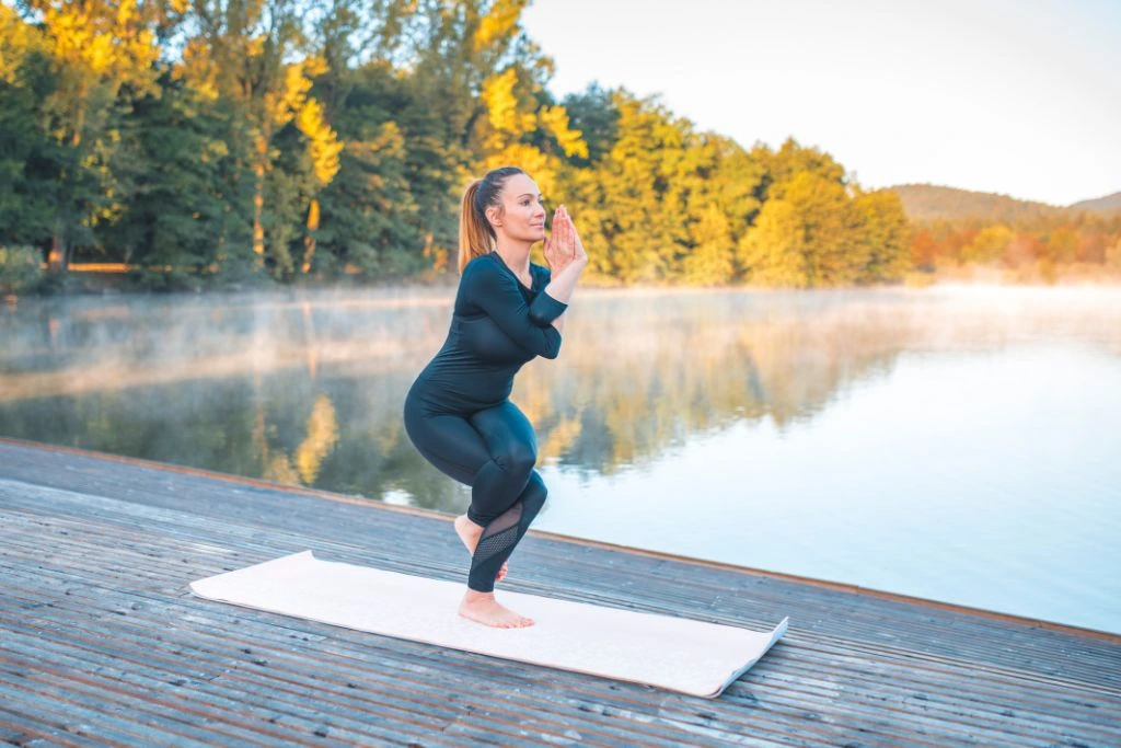 A woman doing a yoga eagle pose in nature