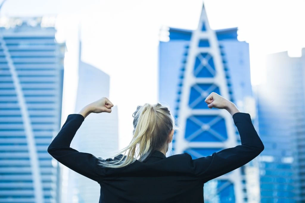 A woman flexing her muscles on top of the building