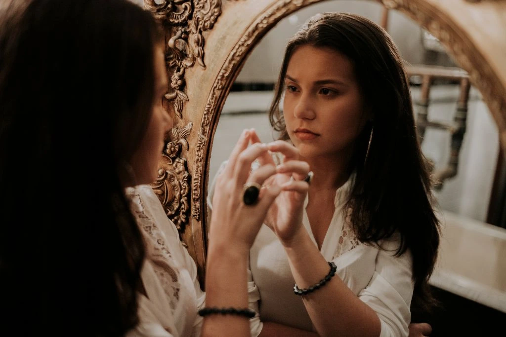 A woman looking at her reflection on the mirror