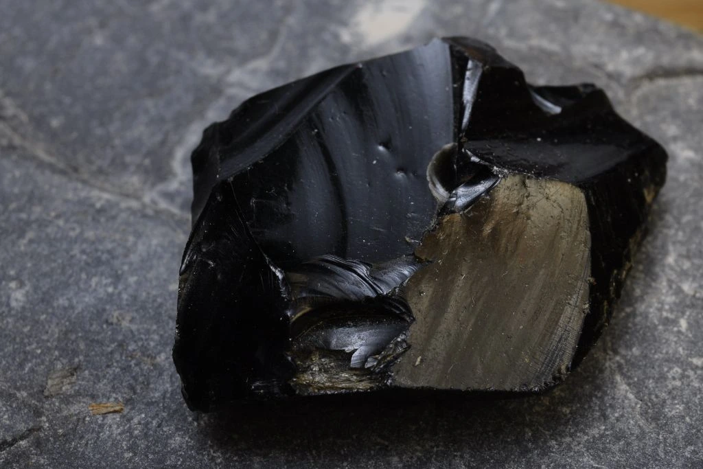 A raw black obsidian crystal on a rock