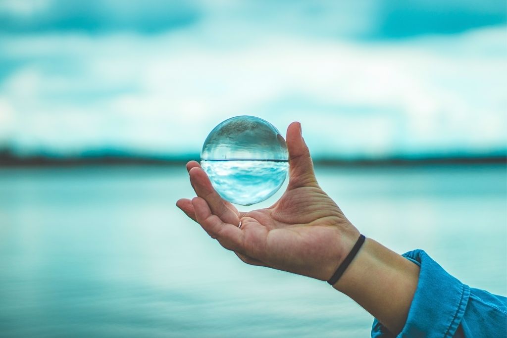a person holding a crystal ball on an ocean background