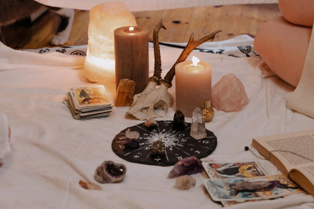 Different kinds of crystals, candles and tarots cards on a white cloth
