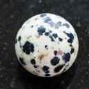 A sphere Dalmatian jasper on a black granite