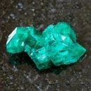 Dioptase crystal on top of a graphite tile