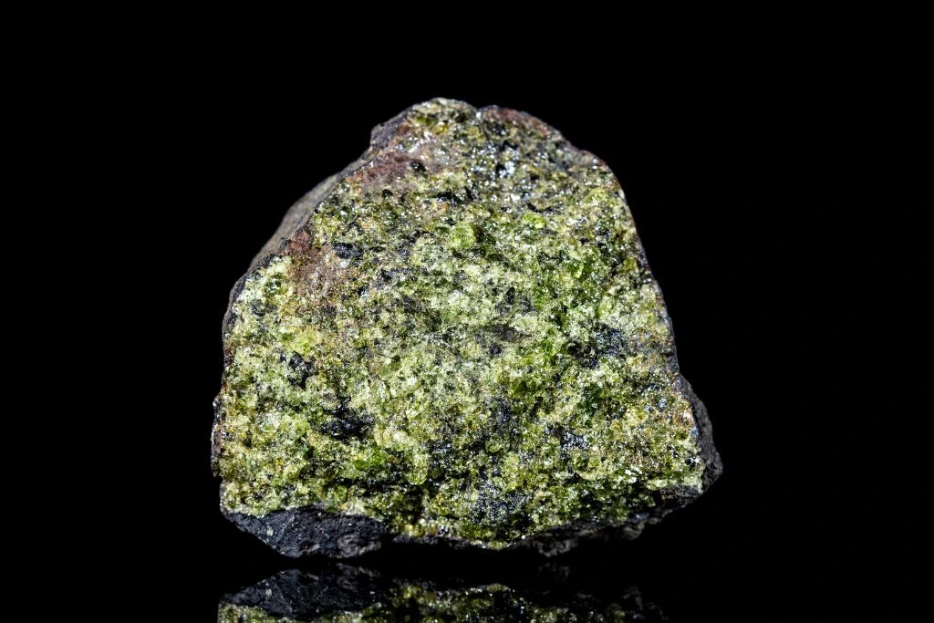 an epidote crystal on a black and reflective background