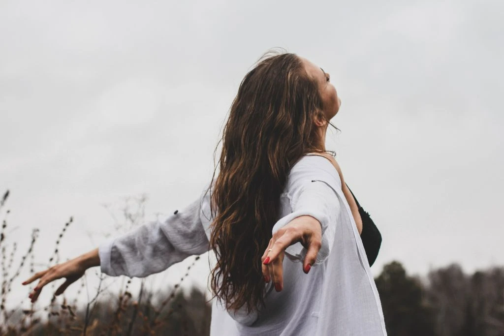 A woman on a field spreading out her arms