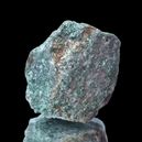 A fuchsite crystal on a black reflective background