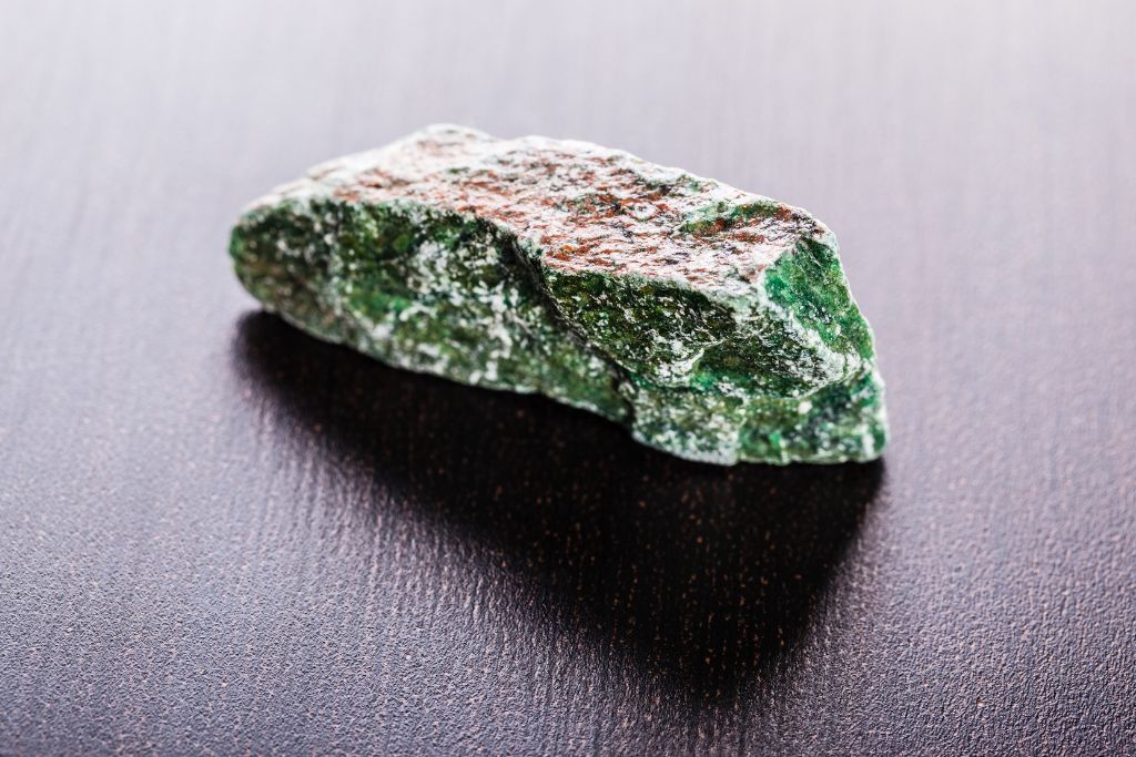 A fuchsite crystal on a wooden background
