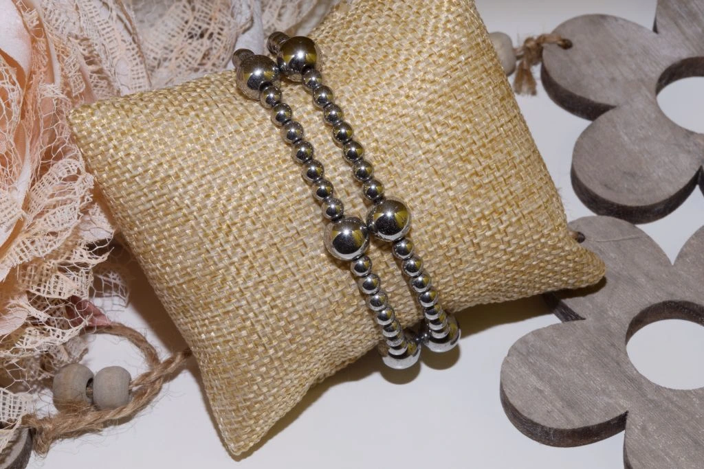 Two pieces of hematite bracelet on a burlap pillow