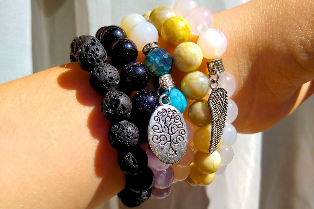 A person is wearing a bracelet made of crystal gemstone