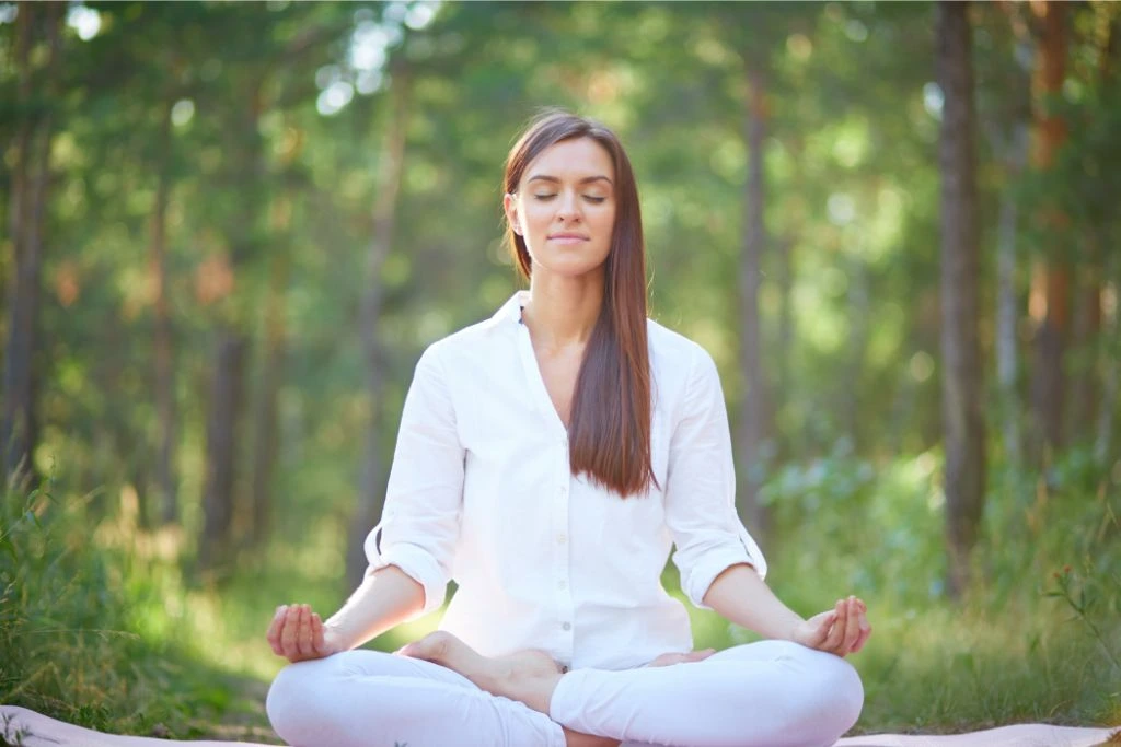 Lady meditating behind several trees