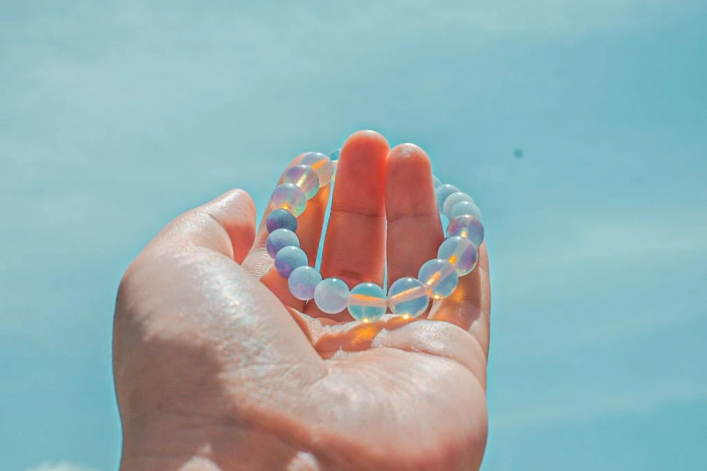 Moonstone bracelet on fingers with blue sky background