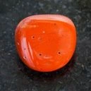 A red coral gemstone on a black granite