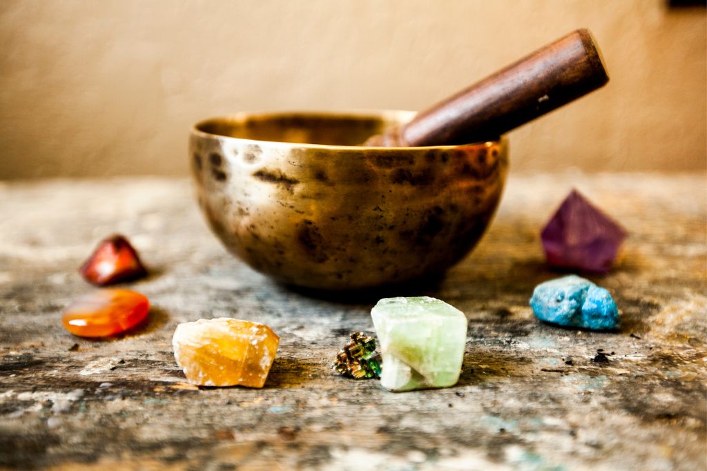 Singing bowl for sound programming and surrounded by different types of gemstones