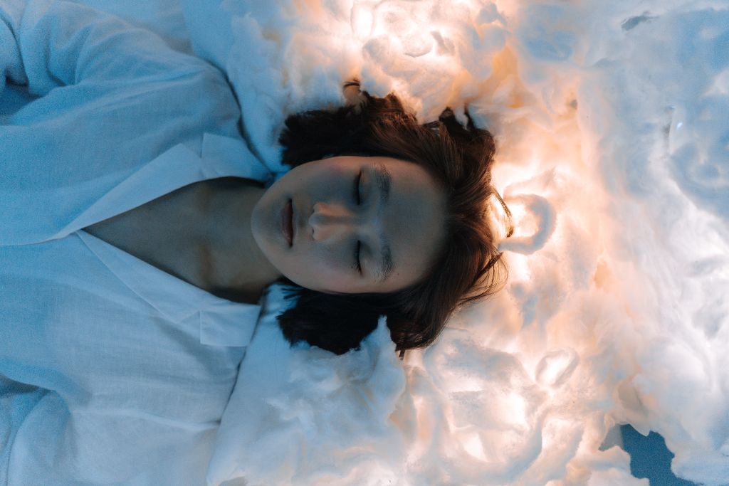 A woman sleeping with dreams depicted on a cloud like picturesque on top of her head. 