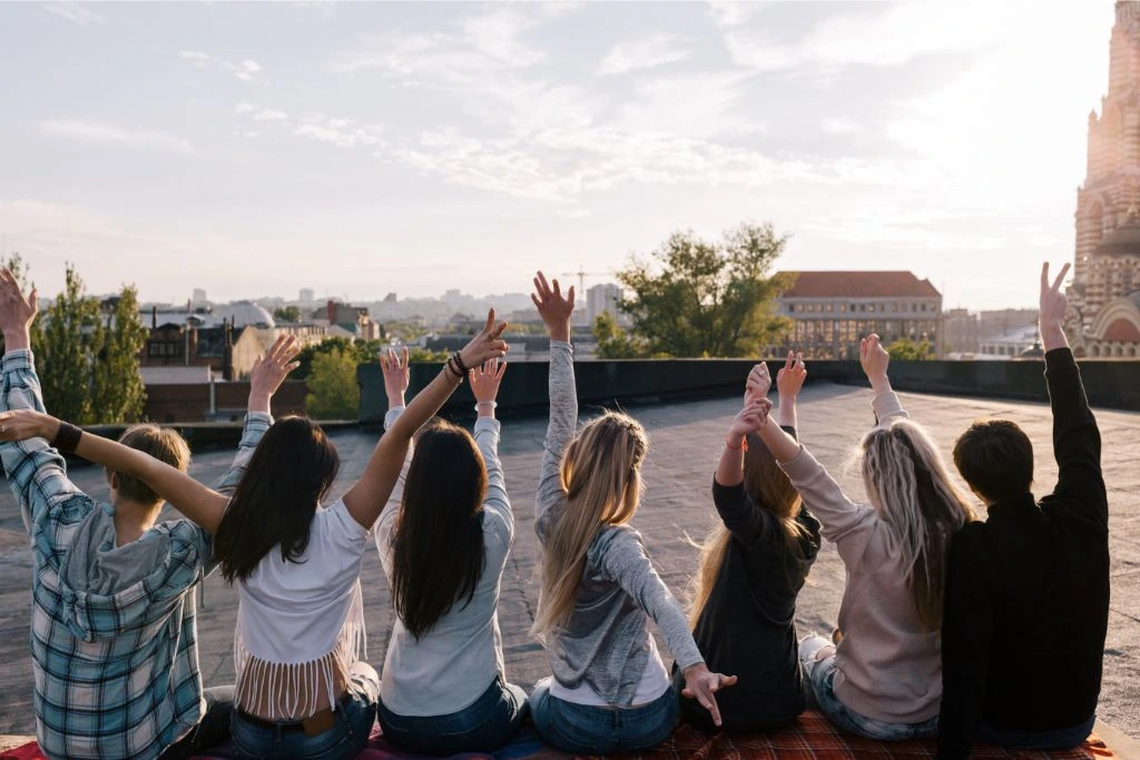 Young people with both their arms raised on a rooftop