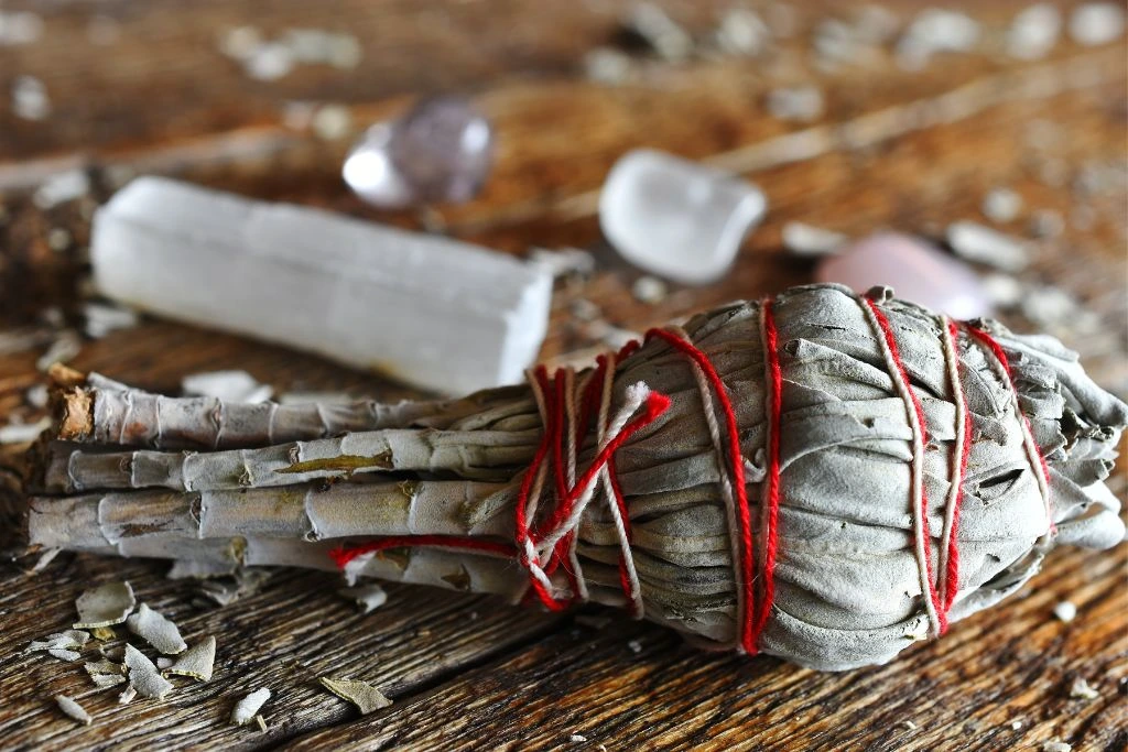 A white sage stick and a selenite wand on a table