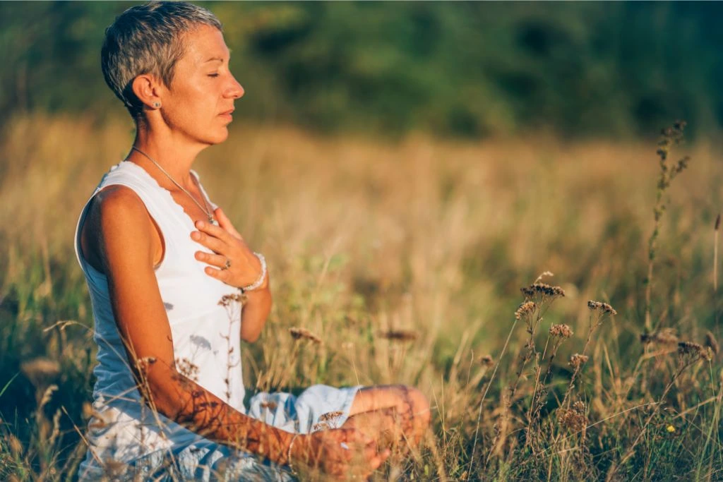 Woman meditating over a grass field