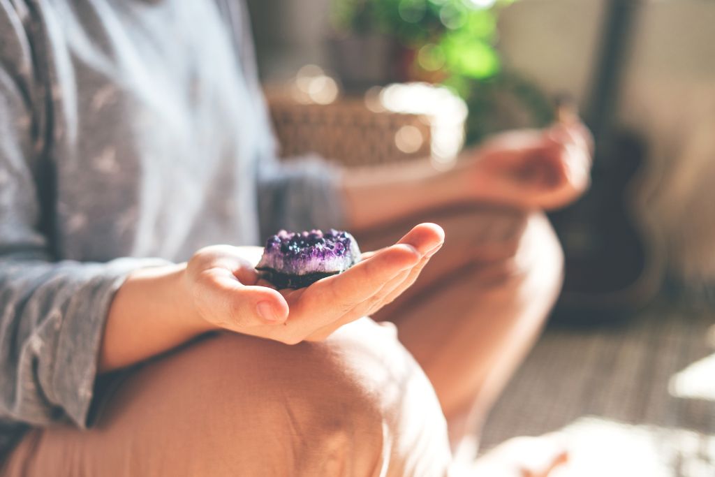 A woman meditating with an Amethyst in hand 