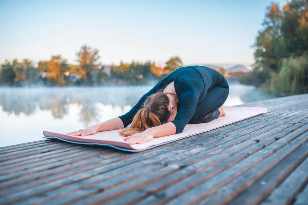 A woman doing a yoga child pose position in nature