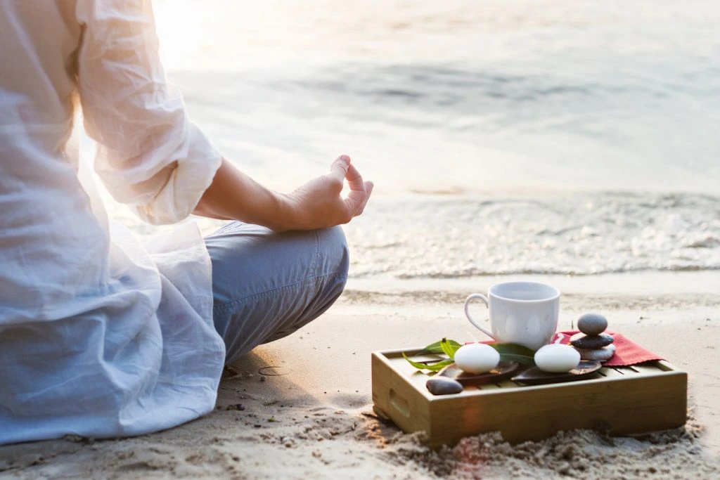 A person meditating near the shore