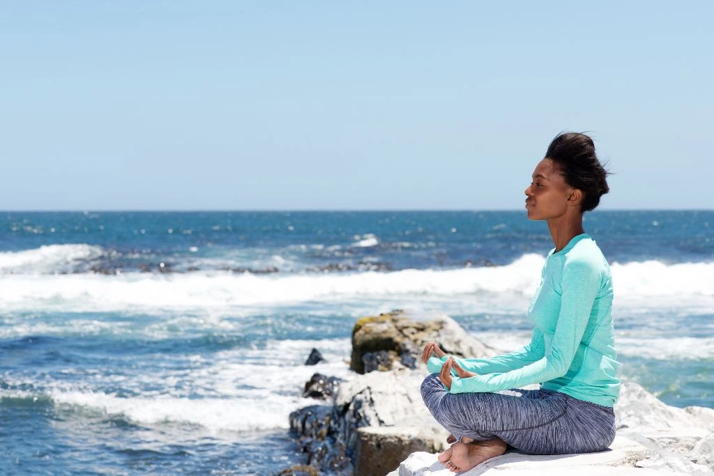 A woman meditating near the shore