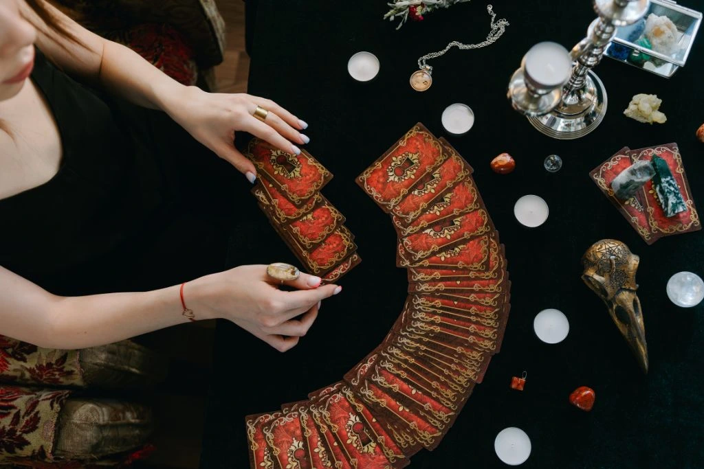 A woman is spreading the tarot card on the table